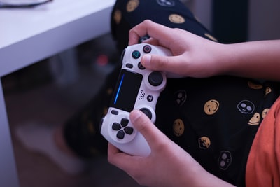 手持白色索尼PS4控制器的人